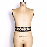 Double strap belt with leather X's and metal O's between the two belts. Belt shown on a dress form.