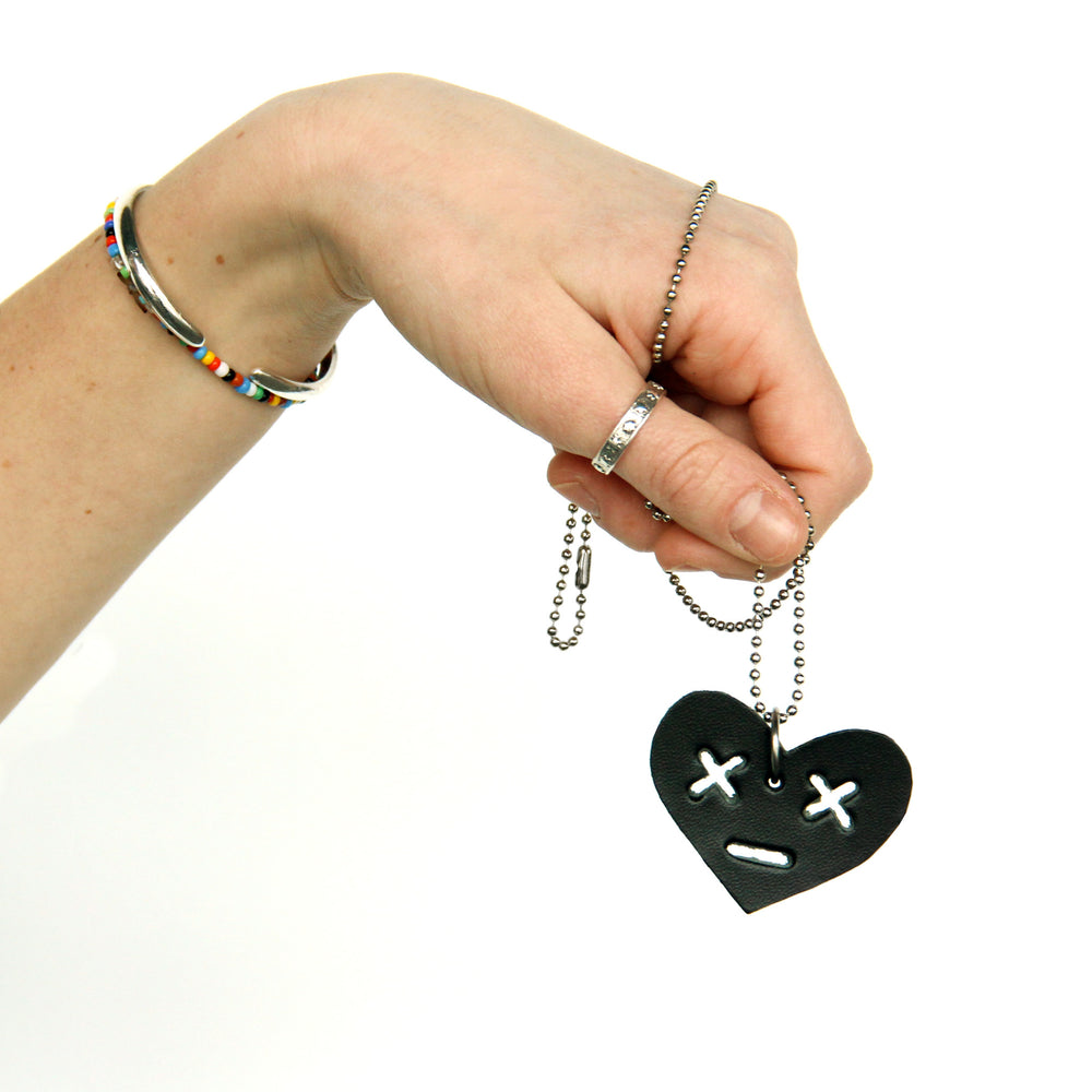 Model holding leather heart necklace