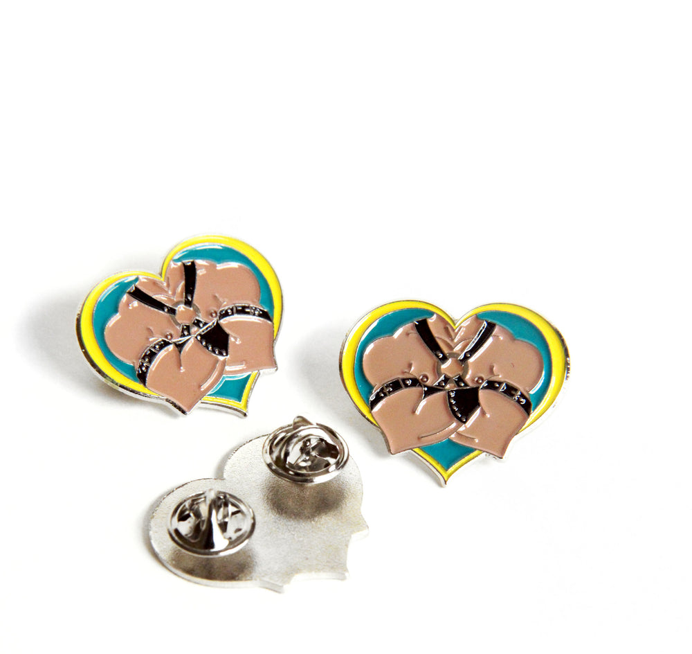 Trio of leather daddy pins on a white background. One is flipped over to show the double butterfly clutch pin backs. 