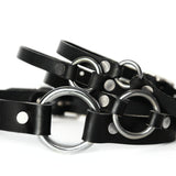 Four black leather chokers sit piled upon one another. On the bottom is the largest o-ring and the smallest is on top.