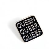 Close up of Q-Words enamel pin. In silver metal letters on a black enamel background, pin reads “Queen, queer, queef.”