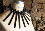Nona Choker shown on a dress form in front of a gritty brick wall. Dramatic lighting highlights the length of the spines.