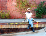 Model poses with legs crossed at a city curb that reads “RESERVED-BUTTERCUP.” Model wears a casual outfit with a Nona Choker.