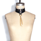 Black leather choker with pearl studs, brass D-ring, and pearl and chain tassel shown on a dress form.