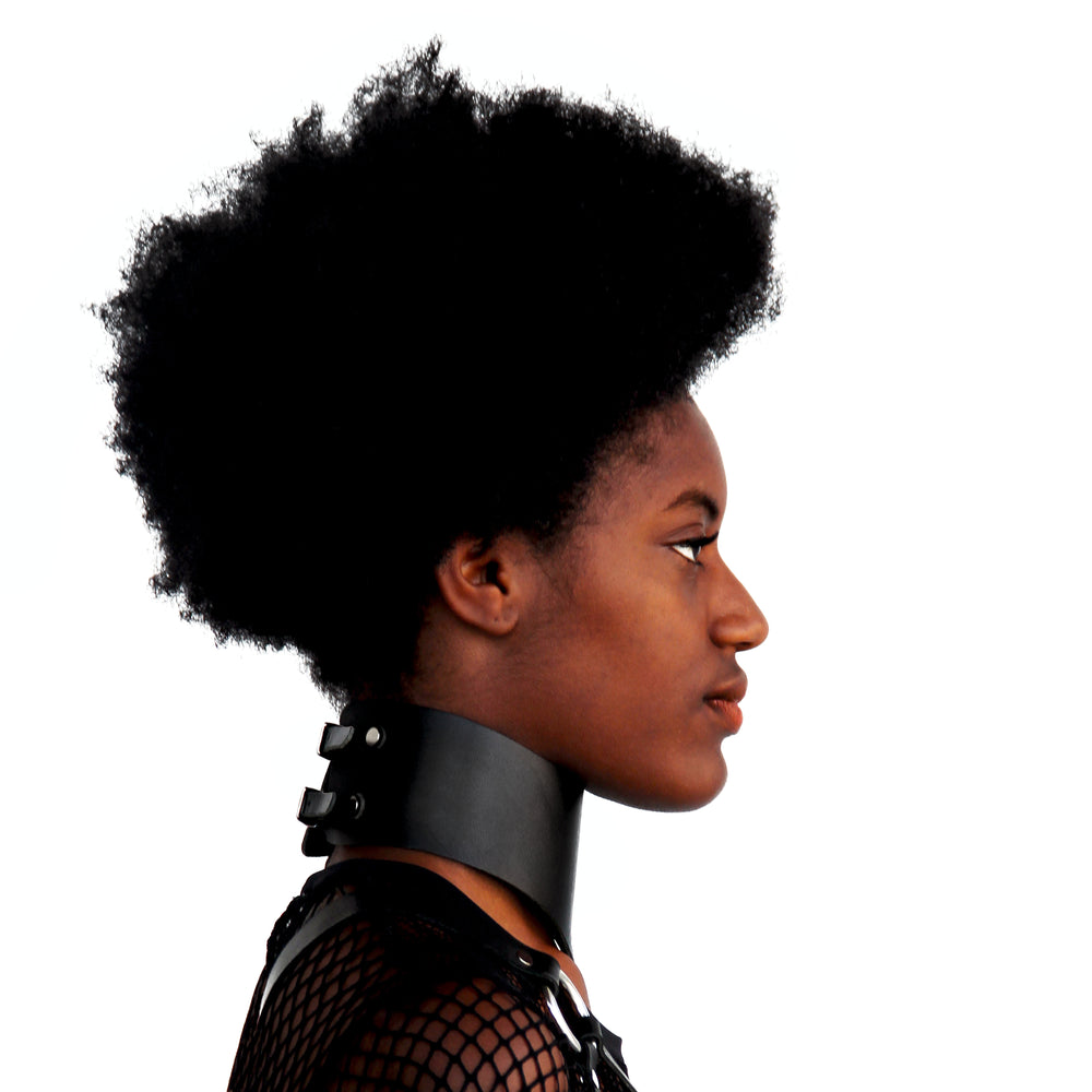 Profile of a model with an afro wearing a posture collar. You an see the double straps that close collar at back.