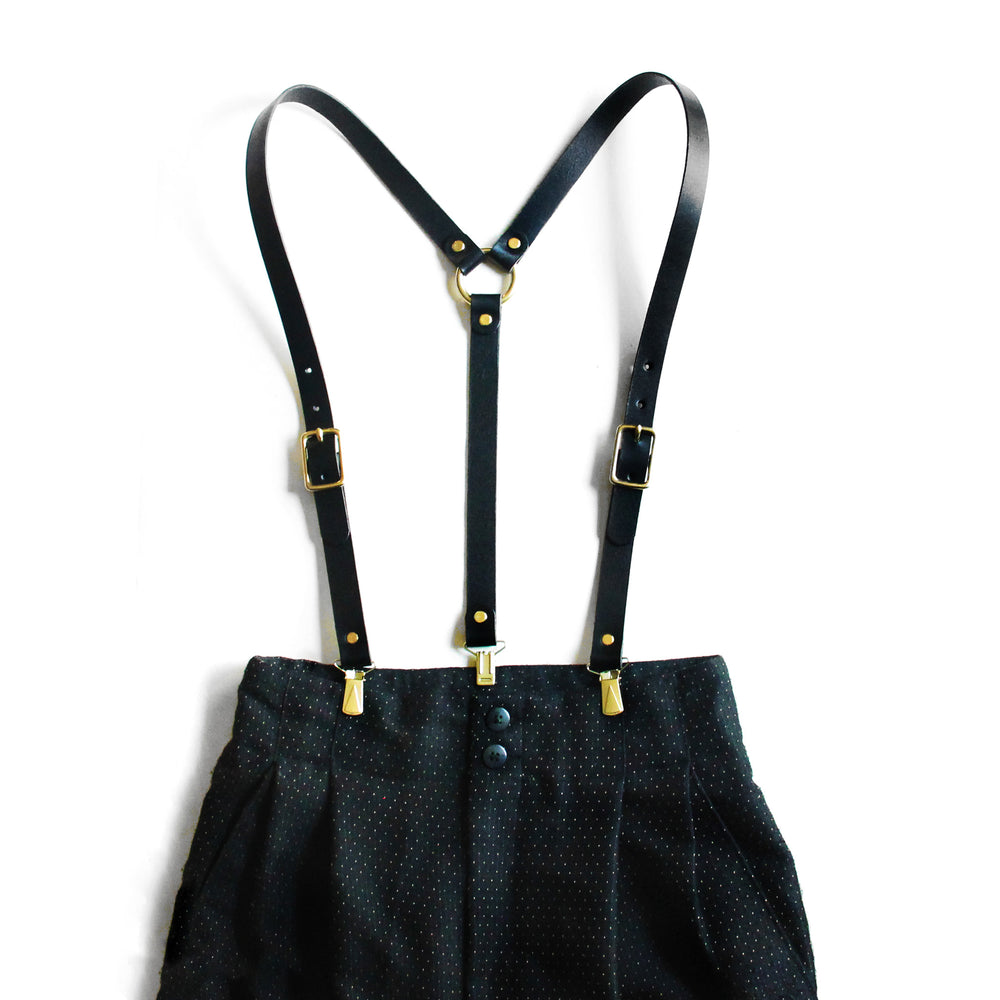 Black leather high-waisted suspenders, with suspender clips and brass hardware on pants