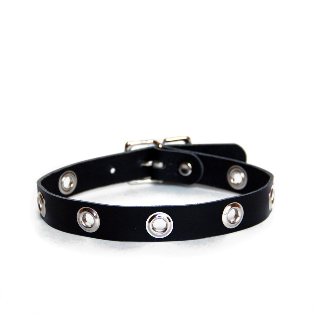 Black leather choker with large grommets and silver hardware on a white background.
