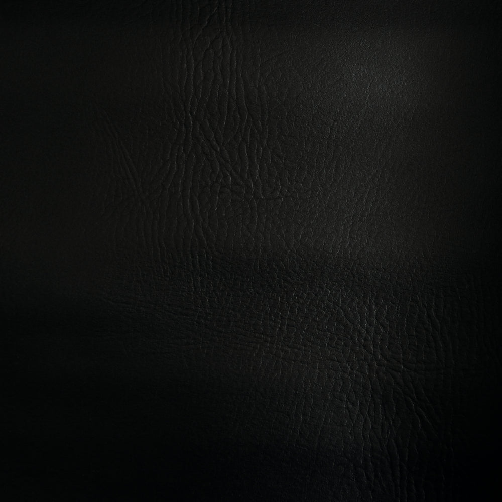 Swatch of black faux leather. Leather grain texture is visible. 