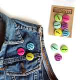 Denim vest adorned with snails, spice, and everything nice pins from the confetti colorway. The rest of the pins lay nearby.