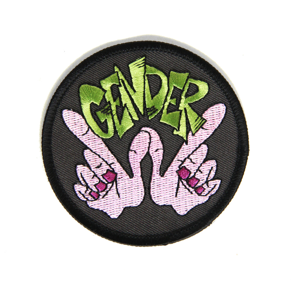Embroidered patch with lime green letters that read “GENDER” with purple hands in the whatever gesture underneath.