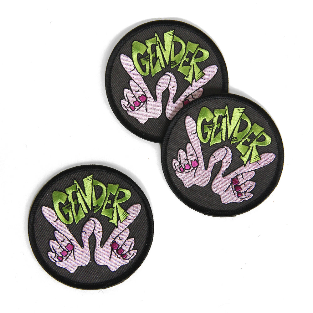 A trio of the Gender Whatever Patch lay on a white background. Patches have grey canvas background and black edging.
