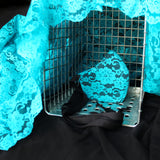 Teal lace face mask in wire cage shown at an angle. Cage is draped with more teal lace fabric.