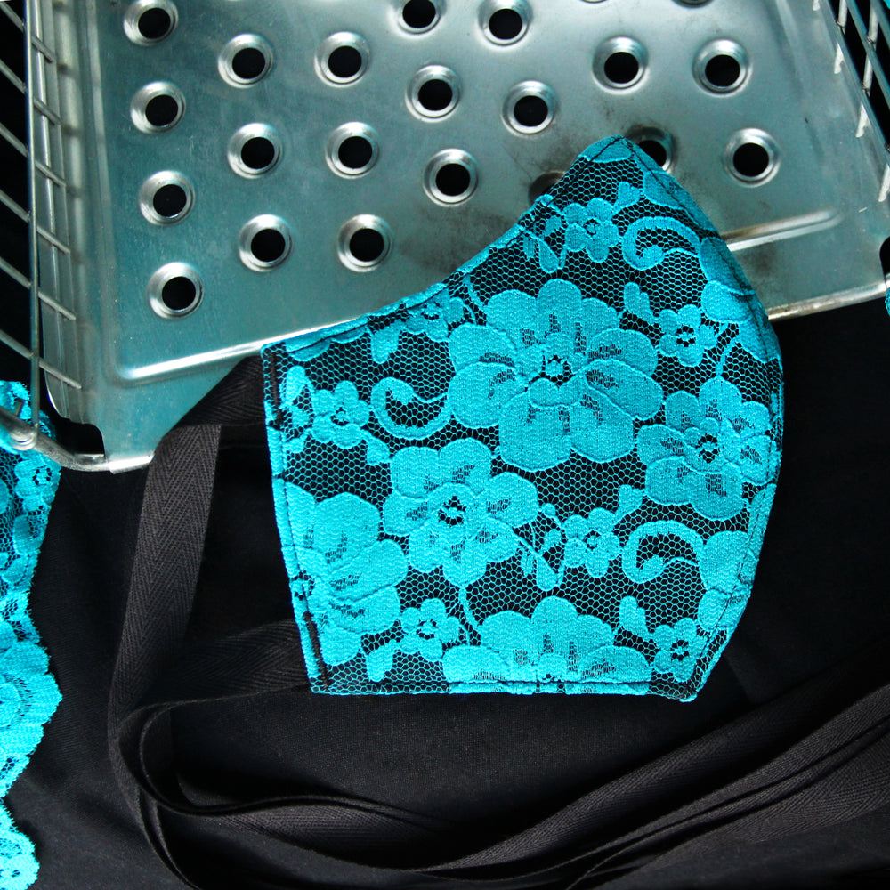 Lace mask laid flat to show shape of mask. Black cotton ties are visible.