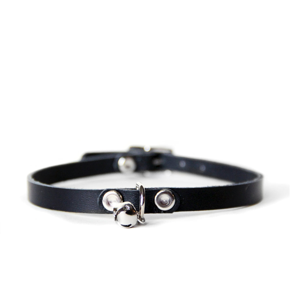 Front view of thin black leather collar with a single jingle bell attached to a d-ring in the front.
